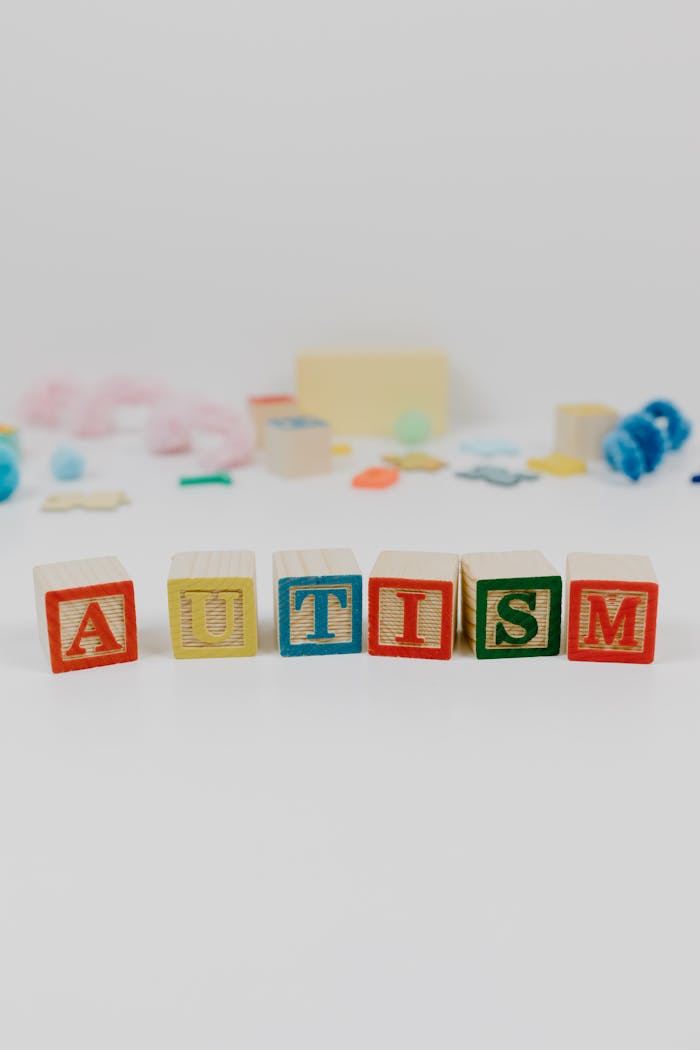 Colorful blocks spelling 'autism' with blurred toys in background.